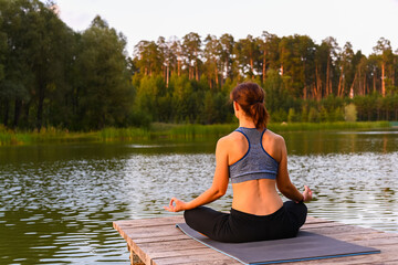 A woman meditates in nature by the lake. The concept of realizing the meaning of life.