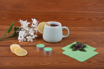 Fototapeta na wymiar a cup of tea with lemon for breakfast. On Valentine's Day.An orchid flower on a branch. A green napkin.Spruce branch. candles in the shape of a heart. Still-life. The concept of Christmas for lovers.