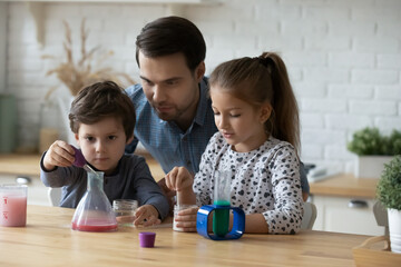 Caring father with little kids playing with toy laboratory, engaged in interesting educational...