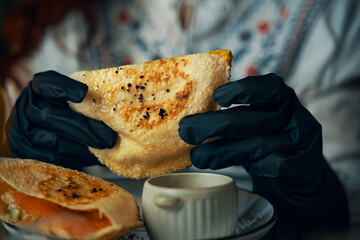 Female hands in black gloves are holding traditional pitas sandwich. Dish of corn bread with fish and salad inside. Cafe menu. Delicious lunch in restaurant.