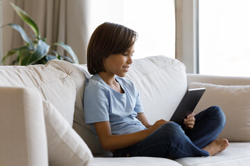 Fototapeta premium Addicted to modern technology happy little preteen kid boy using applications on digital touchpad gadget, web surfing information, playing entertaining games or watching video in social network.