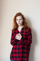 a young girl in a plaid shirt feels bad on a light background