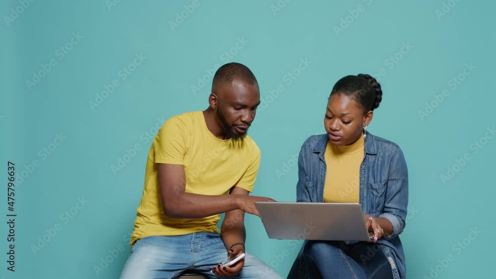 Poster couple having fun with laptop and smartphone in studio. man and woman in relationship using technolo