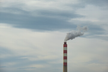 Factory chimney or tower with smoke coming out. Factory pipe pollutes the air in an industrial area. 