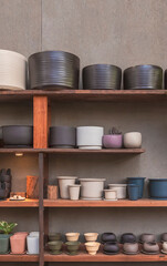 Many various terracotta plant pots on wooden shelf with gray gypsum board wall in vintage tone style and vertical frame