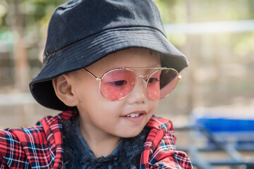 Close up of a boy wearing  hat and fashion glasses.He riding a quad bike on the farm is in a good...