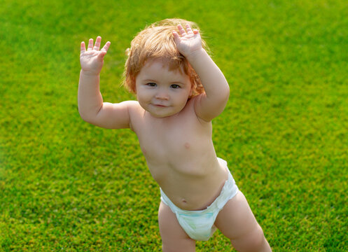 Outdoor kids in diaper activities. Family summer holidays with children. Children in diapers playing in the green grass on summer field. Happy baby boy learning to walk on grass outdoors.