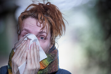 Portrait of a woman who has a cold. She is holding a handkerchief in her hands.