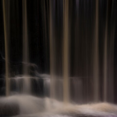 Epic beautiful Autumn landscape image of Nant Mill waterfall in Wales with glowing sunlight on the flowing water