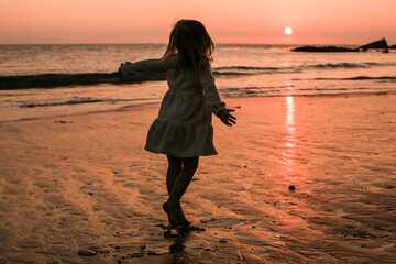 Girl walking on the beach at sunset
