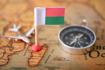 Flag of Madagascar, compass and airplane on the world map.
