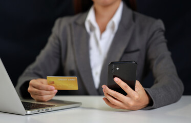 Woman hands sitting and holding credit card and using smart mobile phone and laptop computer on table for online payment or shopping online. Businesswoman using internet for working. E-Banking concept
