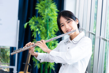 Flute classical instrument profestional player playing song.  A young and elegant Asian woman plays...