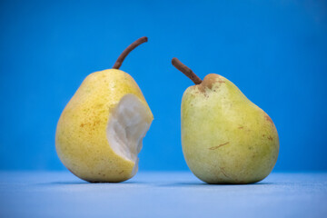  close up of a bitten pear is standing and the background is blue