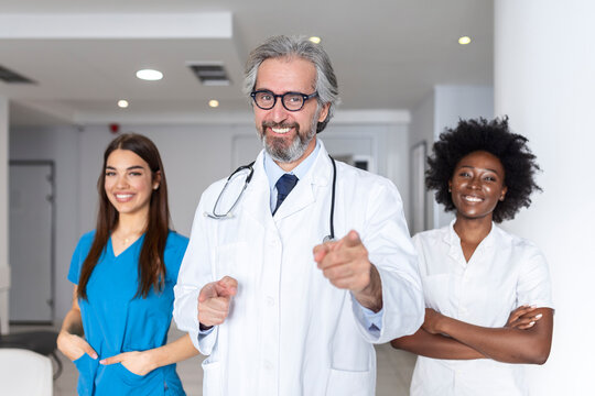 Closeup front view of group of mixed age doctors and nurses standing side by side and looking at the camera. Mature man doctor is in the front