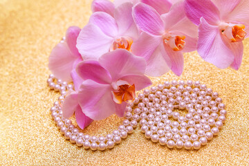 purple Orchid and pearl necklace on a shiny gold background