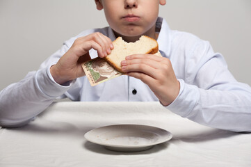 The boy eats a sandwich with five hundreds hryvnias bills stuffed