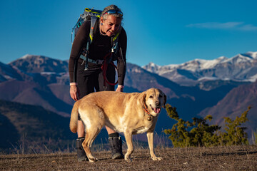 Female hiker and her golden lab dog enjoying a happy hike with amazing view in the French Alps