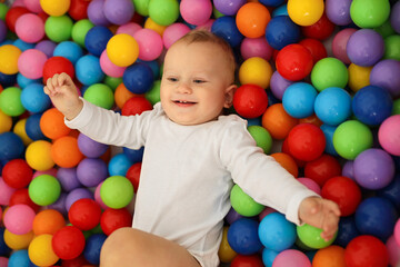 A cute baby is playing in a dry pool with bright plastic balls. The concept of children's leisure. High-quality photography