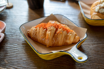 Fresh Baked Salted Egg Lava Croissant, golden brown and crispy French breakfast and snack, served on a tray on wooden table