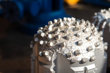 A polycrystalline carbide drill bit, using for drill a subsurface rock structure in oil drilling operation. Oil industrial heavy equipment object photo. Close-up and selective focus.