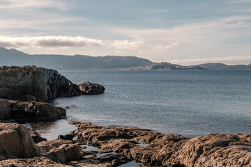 Fototapeta na wymiar The rocky coastline of Corsica at Lumio with the citadel of Calvi in the distance