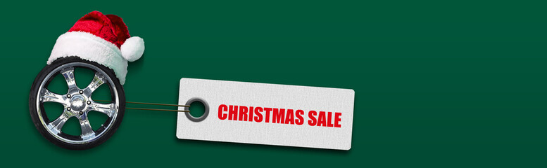 Auto wheel in Santa Claus hat and Christmas sale. The words on the tag, on a green background....