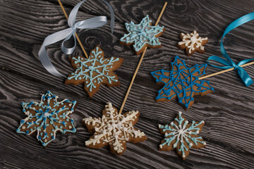 Gingerbread cookies in the shape of a snowflake. Decorated with sugar glaze. Gingerbread cookies on a stick in the shape of a snowflake. Lie on black boards. Close-up shot.