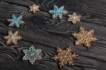 Gingerbread cookies in the shape of a snowflake. Decorated with sugar glaze. Gingerbread cookies in the shape of a snowflake. Lie on black boards. Close-up shot.