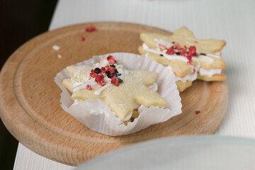Marshmallow sandwiches decorated with chocolate and freeze-dried strawberries. Lie on a round wooden board. Close-up shot.