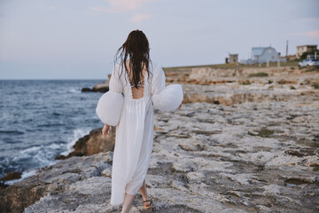 Fototapeta na wymiar Woman walking in white dress on stone beach