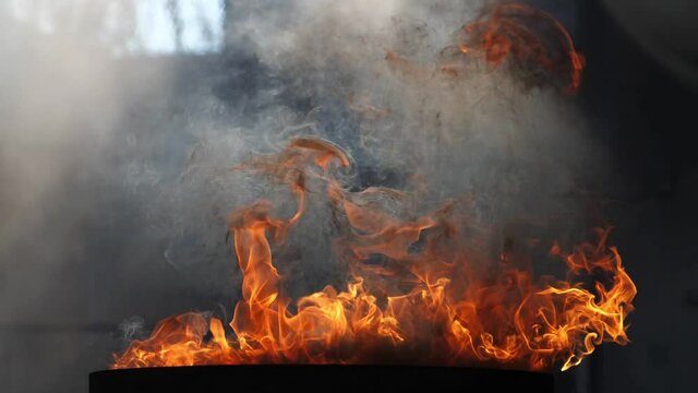 A raging flame of fire in slow motion with rich black smoke. Looks mesmerizing, can be used as a background in video editing
