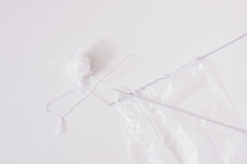 Recycled plastic yarn concept, knitting needles, tangle of sliced plastic package on gray background