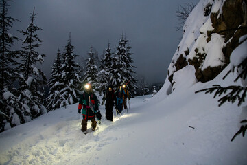 Group of male skiers walking along trail on snowy mountain against the background of snow-covered...