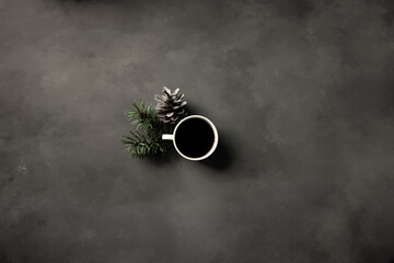 Decoration Made of Gray Pine Cone, Little Cup of Espresso and Green Spruce Twigs. Coffee Time Decoration on a Black-Gray Grunge Background ideal for Card, Banner.