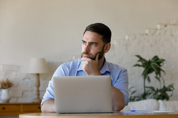 Pensive young businessman entrepreneur worker looking in distance stuck with difficult task,...
