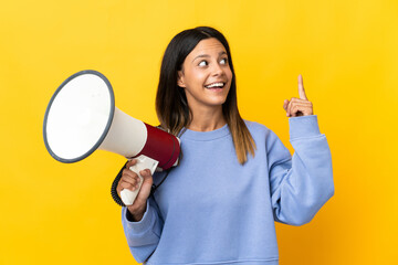 Caucasian girl isolated on yellow background holding a megaphone and intending to realizes the solution - obrazy, fototapety, plakaty