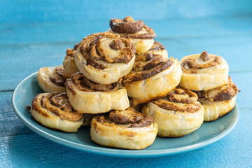 Obraz na płótnie Canvas Puff Pastry Pinwheels stuffed with chocolate on a wooden board