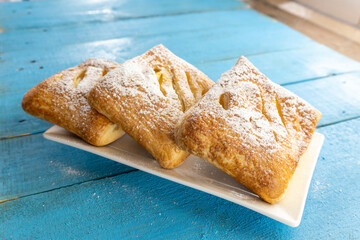Puff pastry apple pastry turnovers for dessert on a wooden table