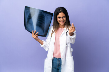 Young doctor woman holding a radiography making money gesture