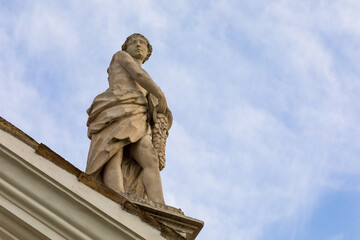 Scultura, vecchia statua che rappresenta la dea della fortuna posizionata sopra un tetto. - obrazy, fototapety, plakaty