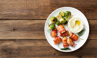 Appetizing Chicken breast wrapped in bacon, garnished with brussel sprout, mashed potato and sage leaves. Holiday food. Wooden  background. Top view.
