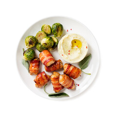 Appetizing Chicken breast wrapped in bacon, garnished with brussel sprout, mashed potato and sage leaves. Holiday food. Isolated on white background. Top view.