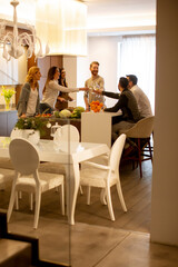 Group of young people preparing meal, drinking white wine and having a good time