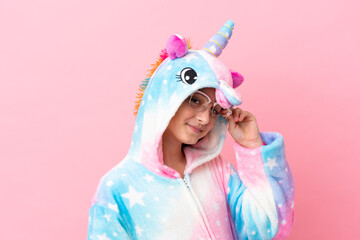 Little caucasian woman wearing a unicorn pajama isolated on pink background © luismolinero