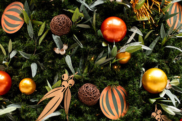 Christmas tree decorated in tropical style with golden and orange ornaments ball. Close up