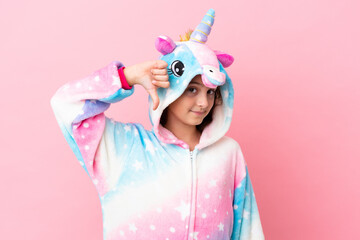 Little caucasian woman wearing a unicorn pajama isolated on pink background showing thumb down with negative expression