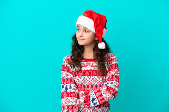 Little caucasian with christmas hat isolated on blue background looking side