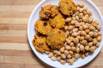 A traditional Indian vegetarian snack Chickpea Sundal and Masala Vada (Lentil Wada) at white plate.