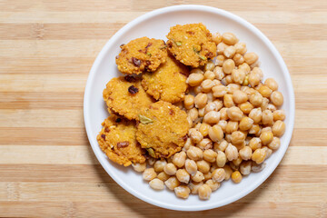 A traditional Indian vegetarian snack Chickpea Sundal and Masala Vada (Lentil Wada) at white plate.